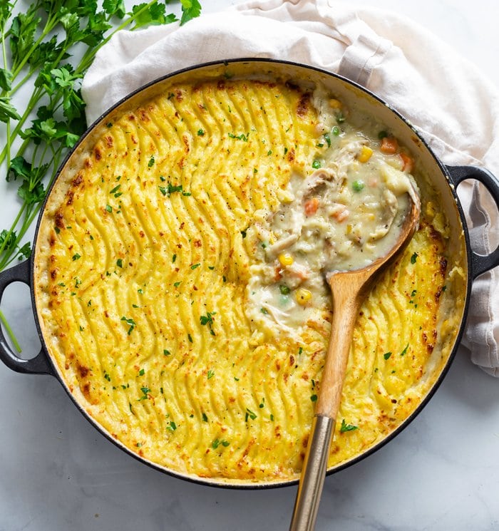 A round dish filled with Chicken Shepherd's Pie with a spoon in it.