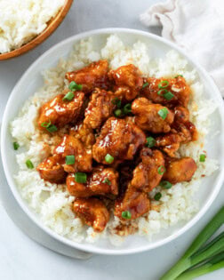 Firecracker Chicken on a bed of white rice with green onions on top.