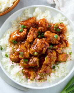 Firecracker Chicken on a bed of white rice with green onions on top.