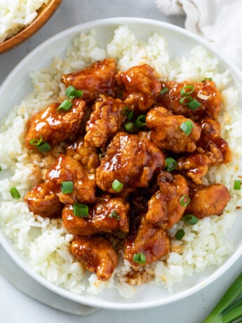 Firecracker Chicken on a bed of white rice with green onions on top.