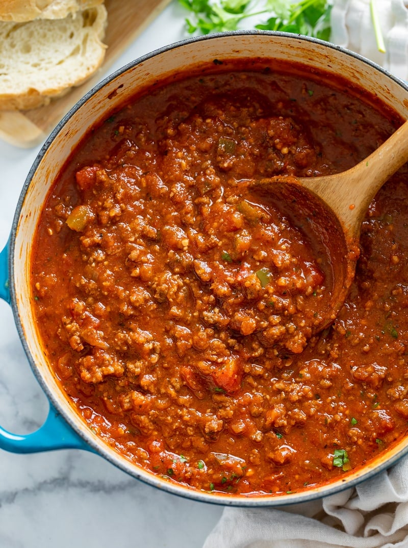 A pot filled with Meat Sauce with a wooden spoon in it.
