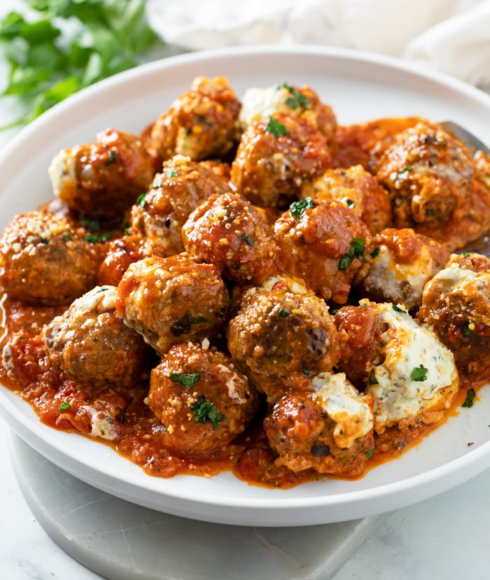 A white plate with Ricotta Meatballs in marinara sauce.