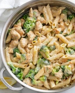 A big pot filled with Chicken and Broccoli Pasta with lemon slices on the side.