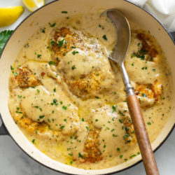 A skillet filled with Chicken in White Wine Sauce with parsley.