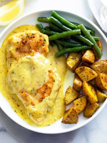 Honey Mustard Chicken on a white plate with green beans and roasted potatoes.