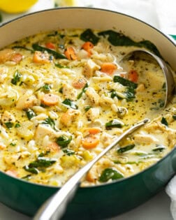 A soup pot with Lemon Chicken Orzo Soup with spinach and vegetables.