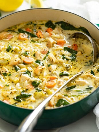 A soup pot with Lemon Chicken Orzo Soup with spinach and vegetables.