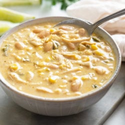 A bowl with a spoon scooping up white chicken chili.