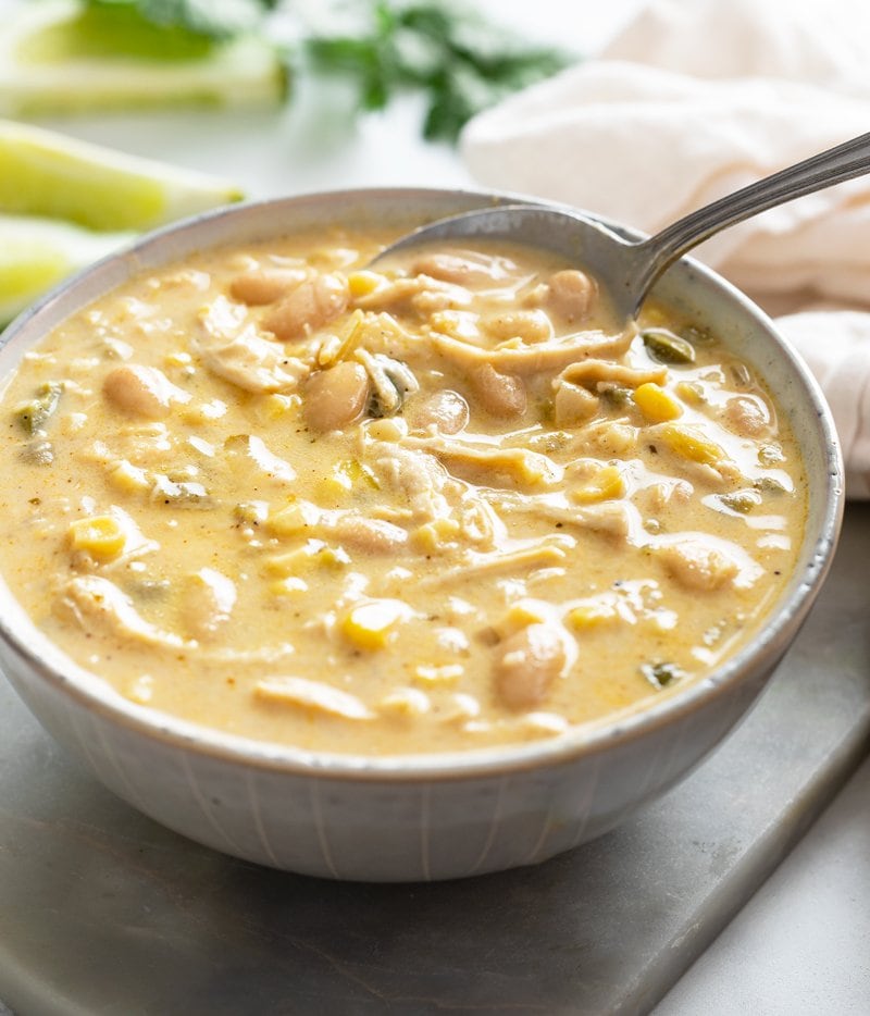 A bowl with a spoon scooping up white chicken chili.