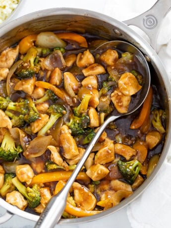 Chicken and Broccoli Stir Fry in a skillet with a spoon on the side.