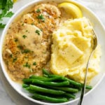 Chicken in White Wine Sauce on a plate with mashed potatoes and green beans.