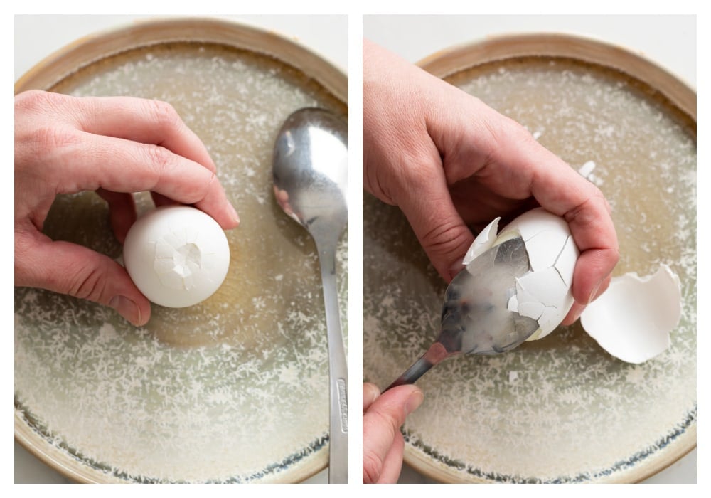 A hard boiled egg being peeled by cracking it and sliding a spoon underneath.