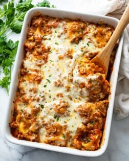 A tray of baked ravioli with a spoon in it.