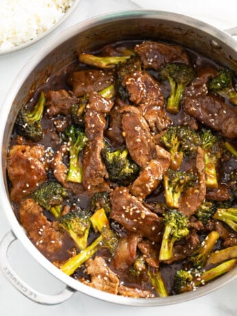 A skillet filled with beef and broccoli in a brown sauce topped with sesame seeds.