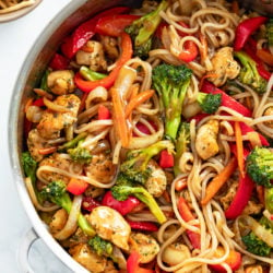 A skillet filled with Chicken Noodle Stir Fry with rice noodles, vegetables and sauce.