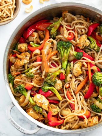 A skillet filled with Chicken Noodle Stir Fry with rice noodles, vegetables and sauce.