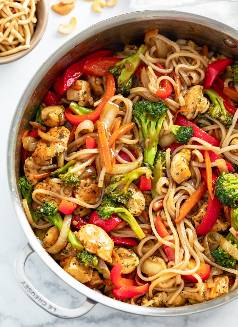 A skillet filled with Chicken Noodle Stir Fry with rice noodles, vegetables and sauce.