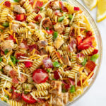 Chicken Pasta Salad in a glass bowl with bacon, tomatoes, bell peppers, and cheese.