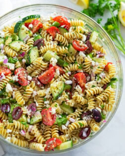 A glass bowl filled with Greek Pasta Salad.