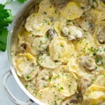 Ravioli in a Creamy Mushroom Sauce in a skillet with fresh parsley on the side.