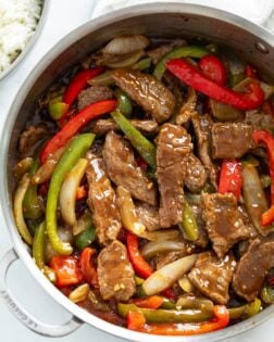 A skillet filled with Pepper Steak in a savory sauce with onions and peppers.