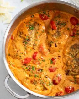 Tomato Chicken in skillet filled with creamy tomato cream sauce and cherry tomatoes.