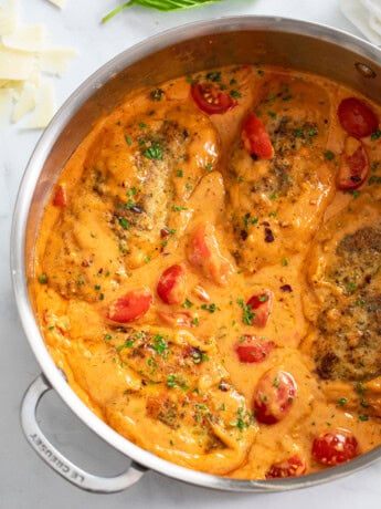 Tomato Chicken in skillet filled with creamy tomato cream sauce and cherry tomatoes.