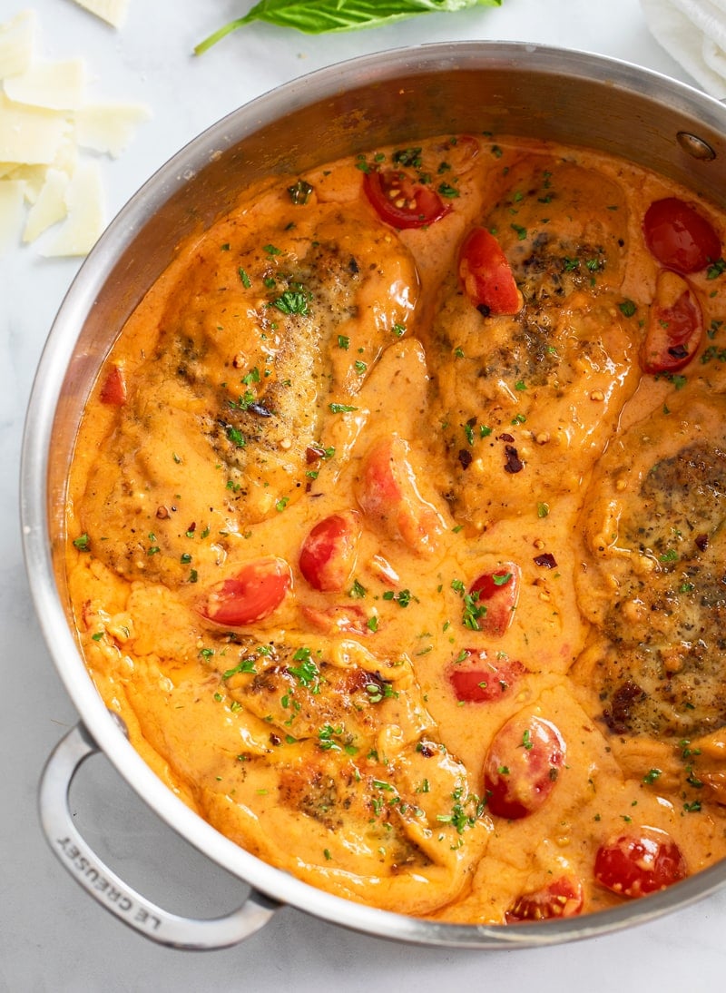 Tomato Chicken in skillet filled with creamy tomato cream sauce and cherry tomatoes.