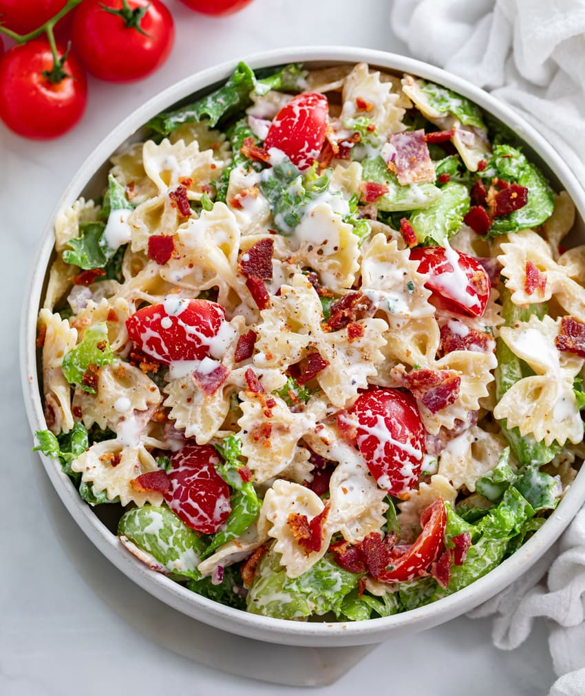 A white bowl filled with BLT Pasta Salad topped with creamy Ranch dressing.