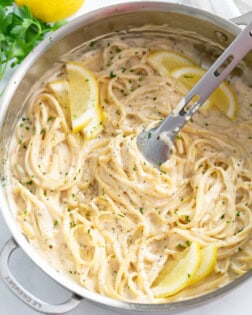 A skillet filled with Creamy Herb Pasta with lemon slices.