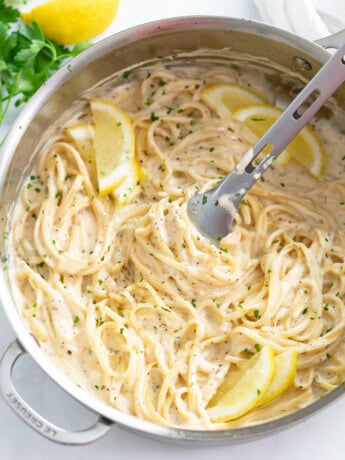 A skillet filled with Creamy Herb Pasta with lemon slices.