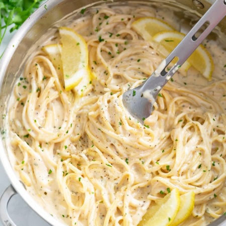 A skillet filled with Creamy Herb Pasta with lemon slices.