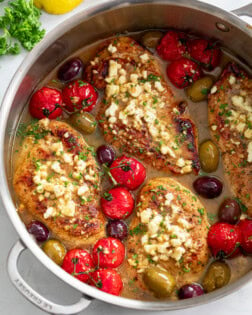 A skillet filled with Greek Chicken in sauce with Feta, tomatoes, and olives.