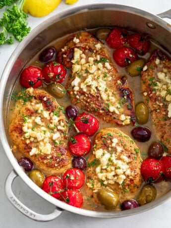 A skillet filled with Greek Chicken in sauce with Feta, tomatoes, and olives.