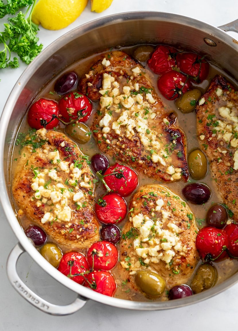 A skillet filled with Greek Chicken in sauce with Feta, tomatoes, and olives.