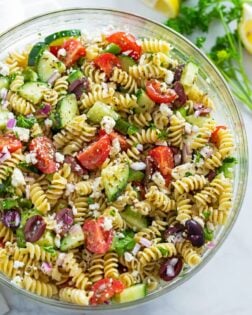 A glass bowl filled with pasta salad and vegetables.