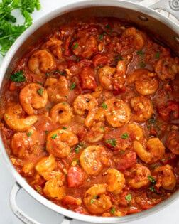 A skillet of Shrimp Fra Diavolo with a spicy tomato sauce and parsley on the side.