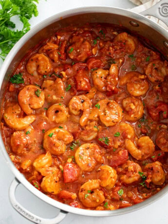 A skillet of Shrimp Fra Diavolo with a spicy tomato sauce and parsley on the side.