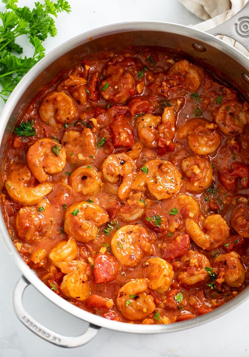 A skillet of Shrimp Fra Diavolo with a spicy tomato sauce and parsley on the side.