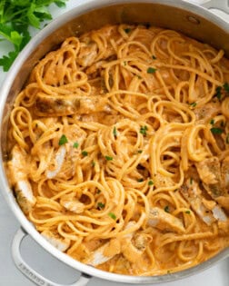 A skillet filled with Creamy Tomato Pasta with Chicken and parsley.