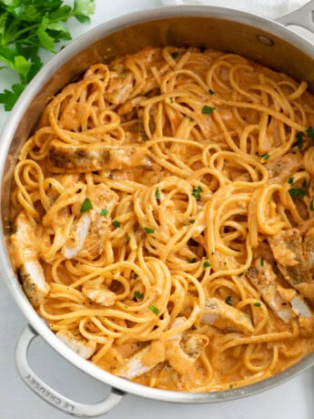 A skillet filled with Creamy Tomato Pasta with Chicken and parsley.