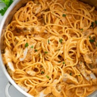 Tomato Chicken Pasta in a skillet with linguine and a creamy tomato sauce.