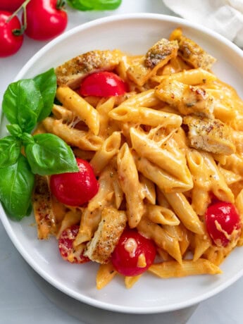 Caprese Pasta with fresh tomatoes and basil on a white plate.