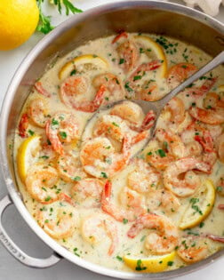 Creamy Garlic Shrimp in a skillet with lemons and chopped parsley.