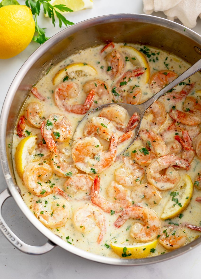 Creamy Garlic Shrimp in a skillet with lemons and chopped parsley.
