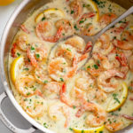 Creamy Garlic Shrimp in a skillet with lemon slices and a spoon.