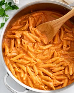 A skillet filled with Pink Sauce Pasta with a wooden spoon.