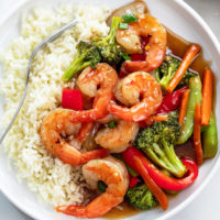 Shrimp Stir Fry on a white plate with rice and brown sauce.