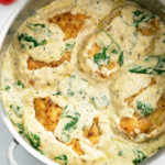 Chicken breasts in a creamy spinach sauce in a skillet.