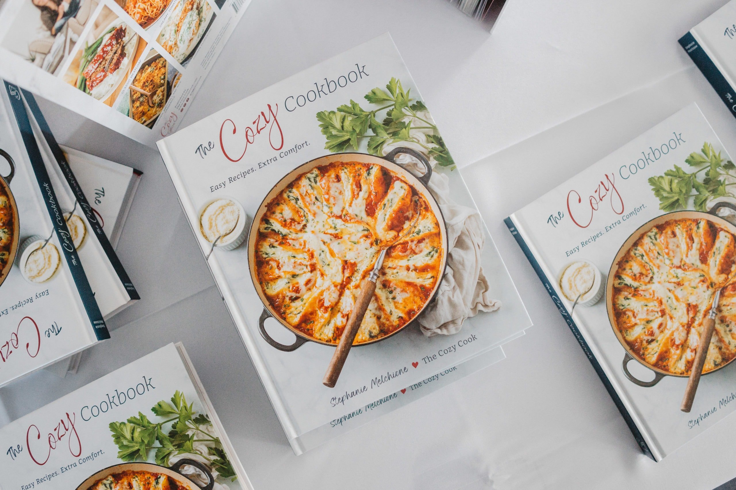 The Cozy Cookbook on a table next to other Cozy Cookbooks.